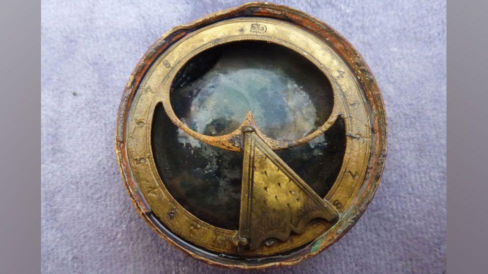 An round bronze sundial compass with numbers on a thin outer circle of bronze