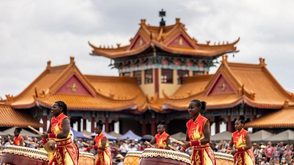 drummers in traditional chinese clothing performing in south africa by a temple