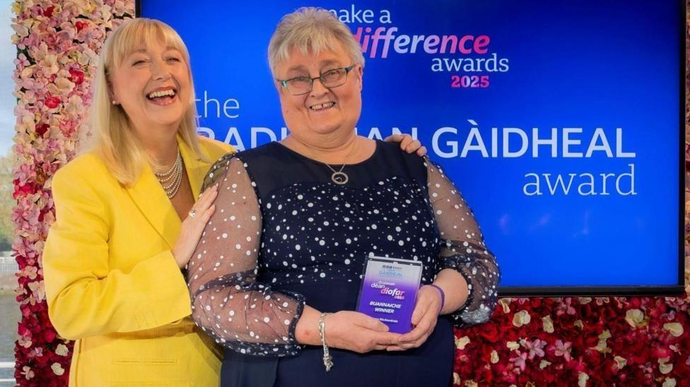 Seonag NicAnndrais a' faighinn na duaise aice an-uiridh bho Chathy NicDhòmhnaill