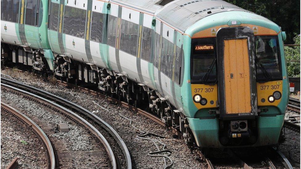 A green and white Southern train travels along a track