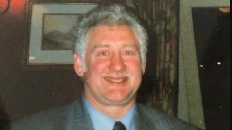 James Joseph Corrigan wearing a suit and tie with grey hair and moustache 