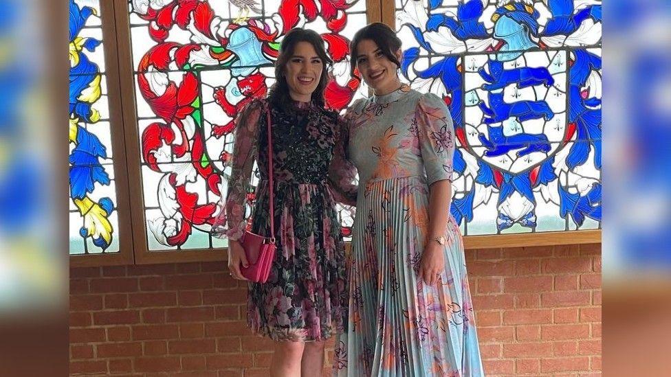 Georgia and Melissa both dressed very smartly with a stained glass window behind them