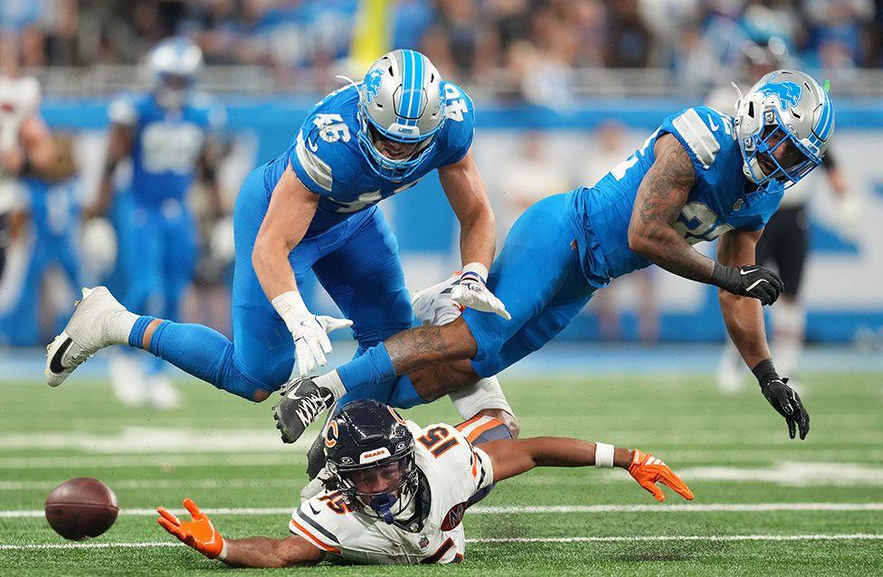 Rome Odunze of the Chicago Bears attempts to complete a catch under pressure from Detroit Lions pair Jack Campbell and Brian Branch. Photo by Nic Antaya
