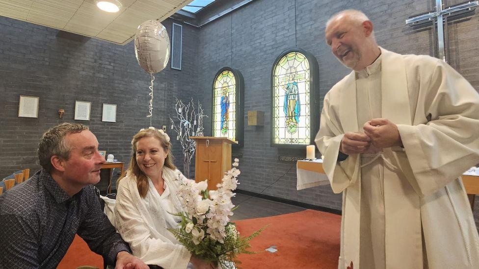 Emily and Jamie Cross in the chapel at the Royal Preston Hospital while the chaplain stands to the right laughing