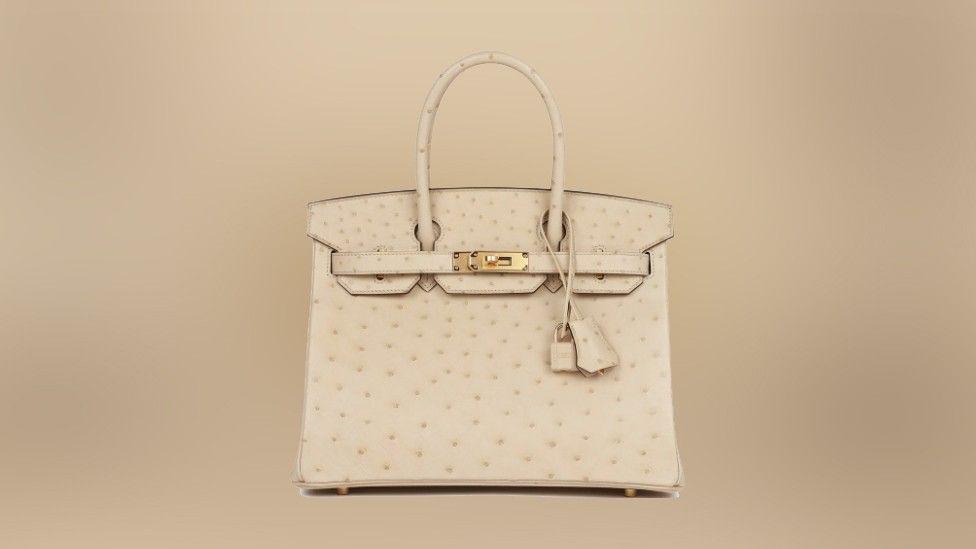 A cream bag with a gold clasp on a beige background