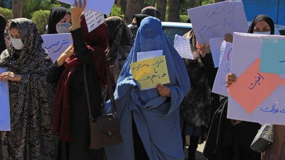 A group of Afghan women in holding up banners in protest.