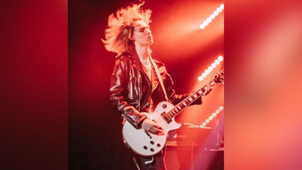 Teenager playing white electric guitar