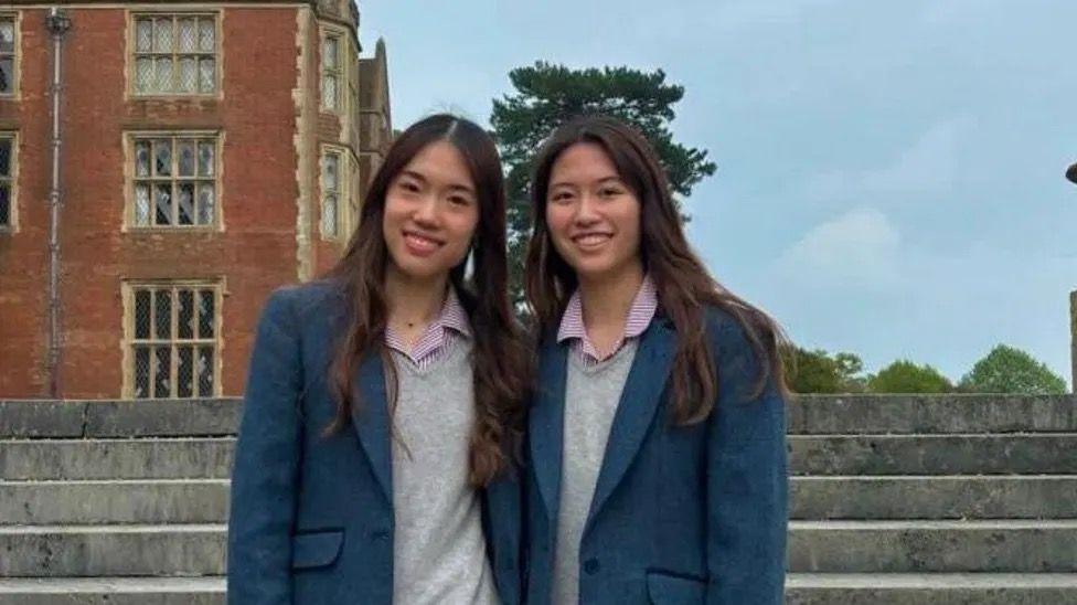 Nicola and Victoria Tsang in their school uniforms smiling.