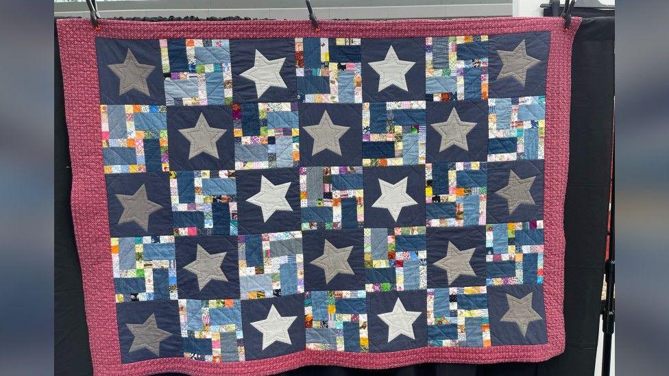 Quilt with a red border and blue squares with white and grey stars