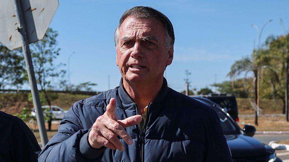 Brazil's former President Jair Bolsonaro gestures as he arrives to the State Secretariat of Penitentiary Administration headquarters in Brasilia, Brazil 