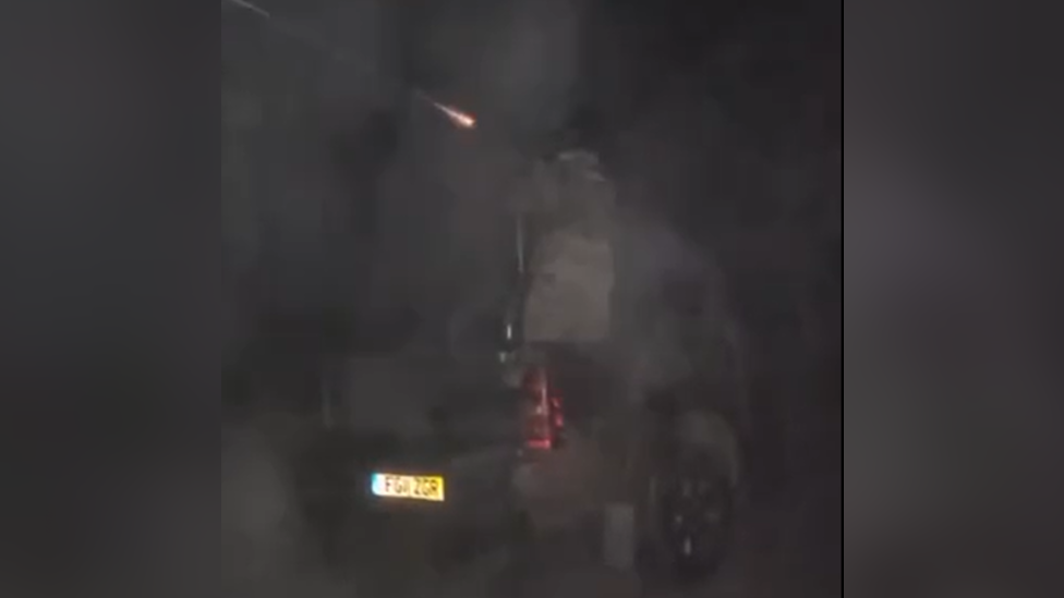 A grainy photo in which a gun is shown being fired, with a soldier on the back of the pick-up truck donated by Alistair Caldwell.