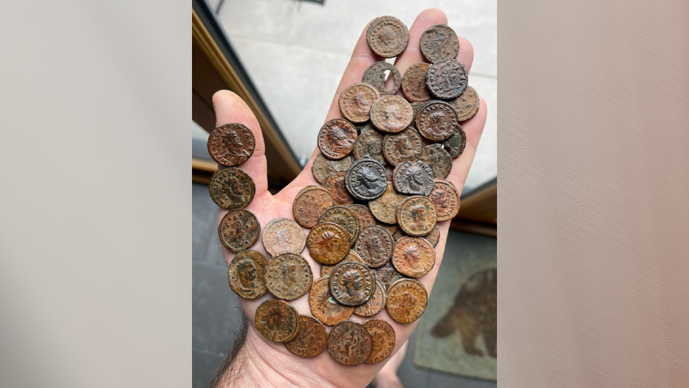 Many old brown coins laid on the palm of a person's hand