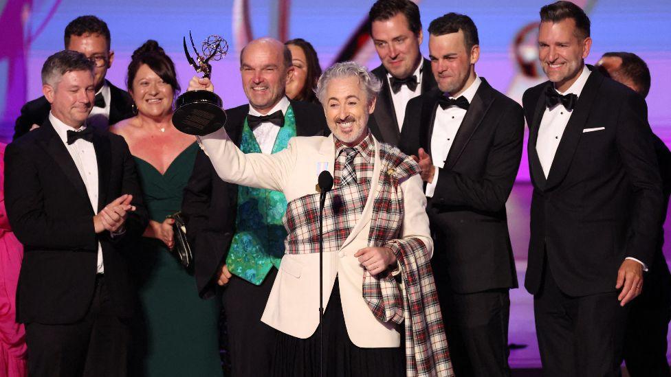 Alan Cumming, accompanied by cast and crew, receives the Best Competition Program award for "The Traitors" at the 76th Primetime Emmy Awards in Los Angeles, California, U.S., September 15, 2024