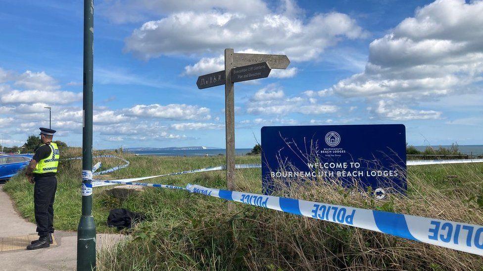 Policeman standing next to tape at clifftop crime scene