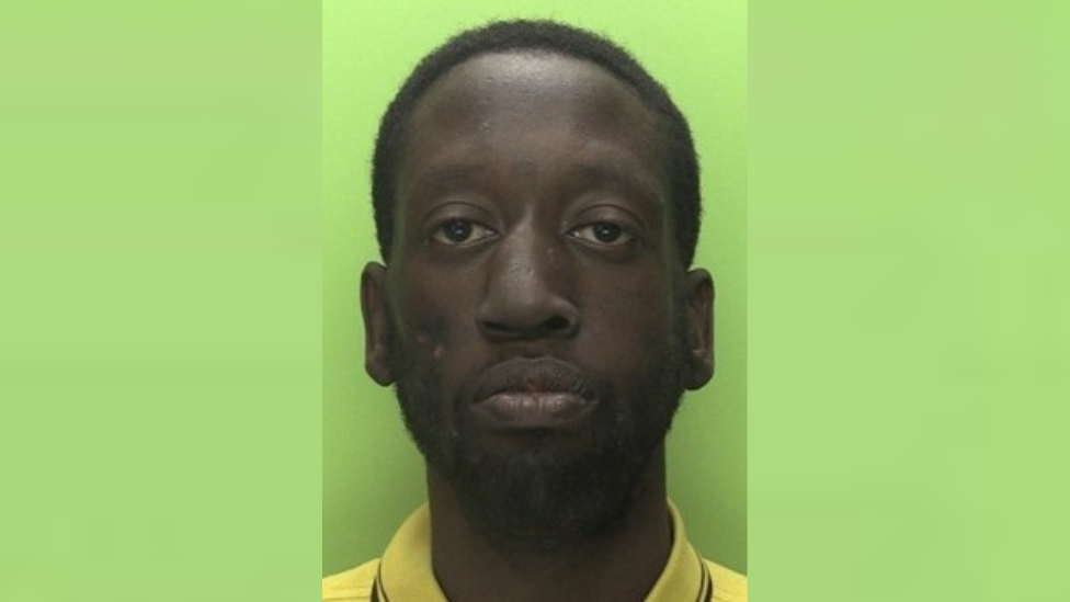 A headshot of Ashley Lawrence, with short dark hair and beard, wearing a yellow collared shirt.