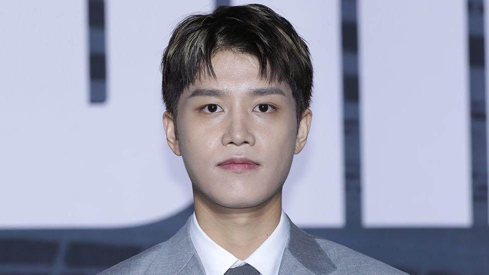 Taeil, former member of the K-pop band NCT, dressed in a gray suit, white shirt and gray tie, poses for the camera at a press conference in Seoul, in September 2022