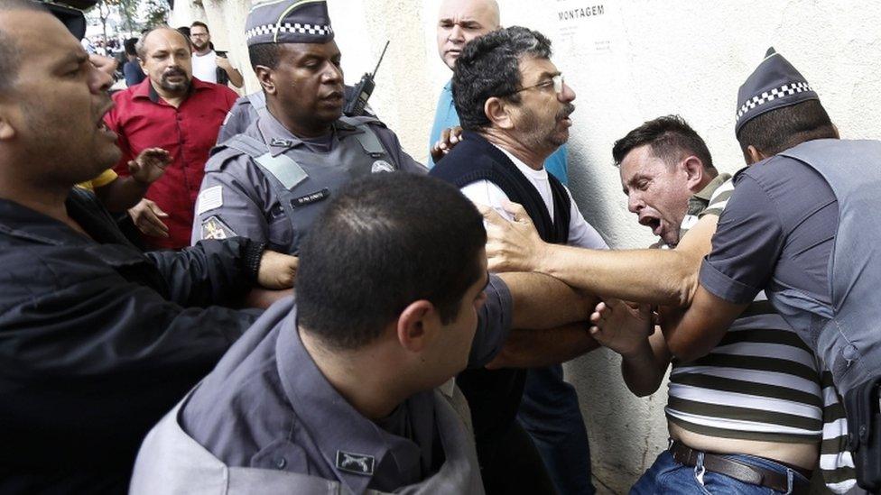 A supporter of former Brazilian president Luiz Inacio Lula da Silva struggles with police near his home, 4 March