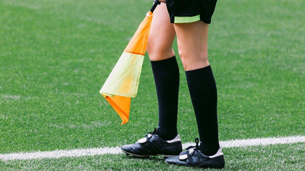 Close up of a female assistant referee holding a flag