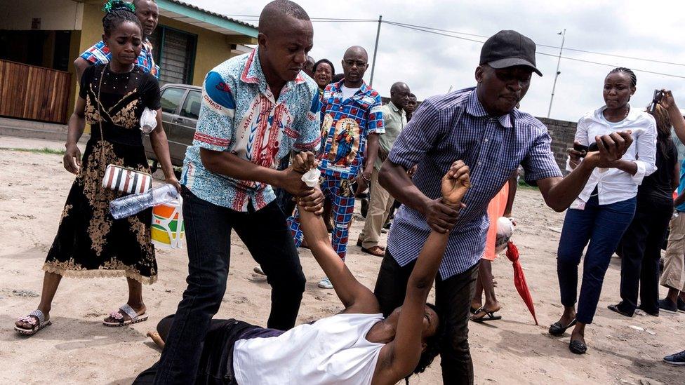 A relative of a man who succumbed to a gun shot wound is carried by two men during a protest called by the Catholic Church on February 25, 2018 in Kinshasa.