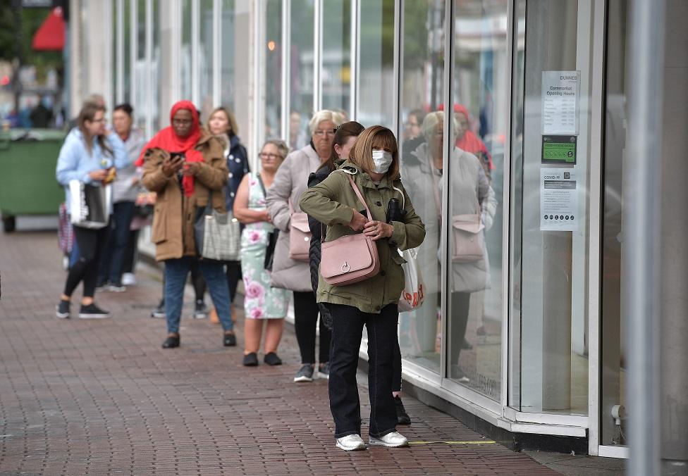 Shoppers queue outside Dunnes Stores clothing shop on June 12, 2020 in Belfast, Northern Ireland. After being shuttered for months to curb the spread of Covid-19, retailers here reopened with social distancing measures, a few days ahead of when similar businesses can reopen in England.