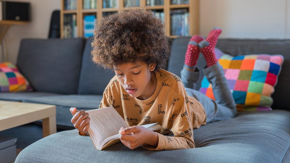 Child reading a book on the sofa