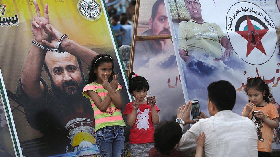 A Palestinian father takes photos of his daughters as they stand in front of a poster of imprisoned Fatah leader Marwan Barghouti, during a sit-in held in Gaza City to show solidarity with Palestinian prisoners on hunger strike in Israeli Jails (30 April 2017)