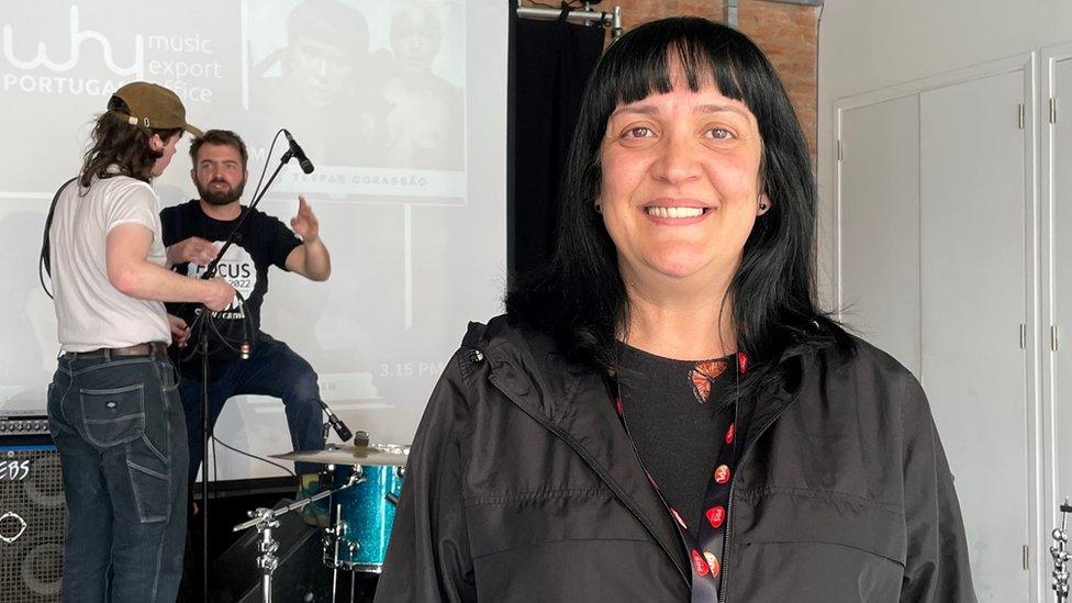 Iolanda Banu Viegas at Hope St Church in Wrexham, with people setting up a band on stage behind her