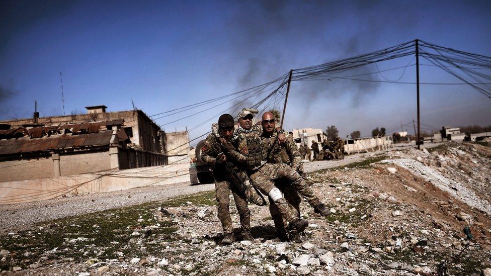 Members of Iraq's elite Rapid Response Division carry a wounded comrade in the northern city of Mosul, as Iraqi forces continue the offensive to retake the city's western half from Islamic State (IS) group fighters, on February 25, 2017