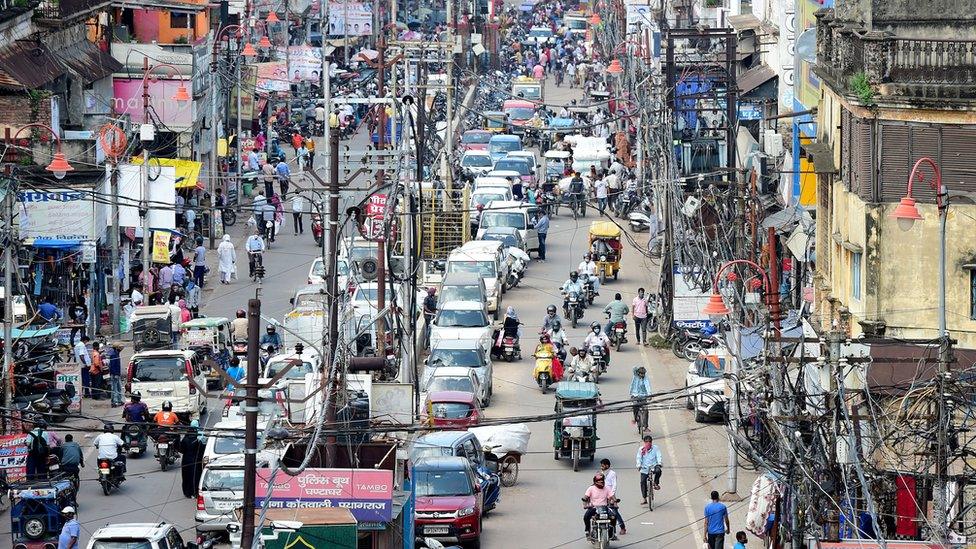 Commuters are seen along a road in the old neighbourhood of Chowk, in Allahabad on August 17, 2020.