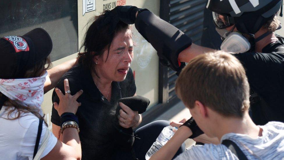 A protester suffering the after-effects of tear gas is assisted by a journalist