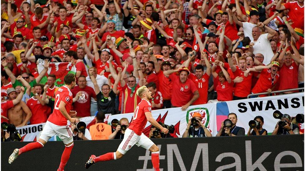 Fans go wild after Aaron Ramsey (r) scores an early goal to put Wales ahead