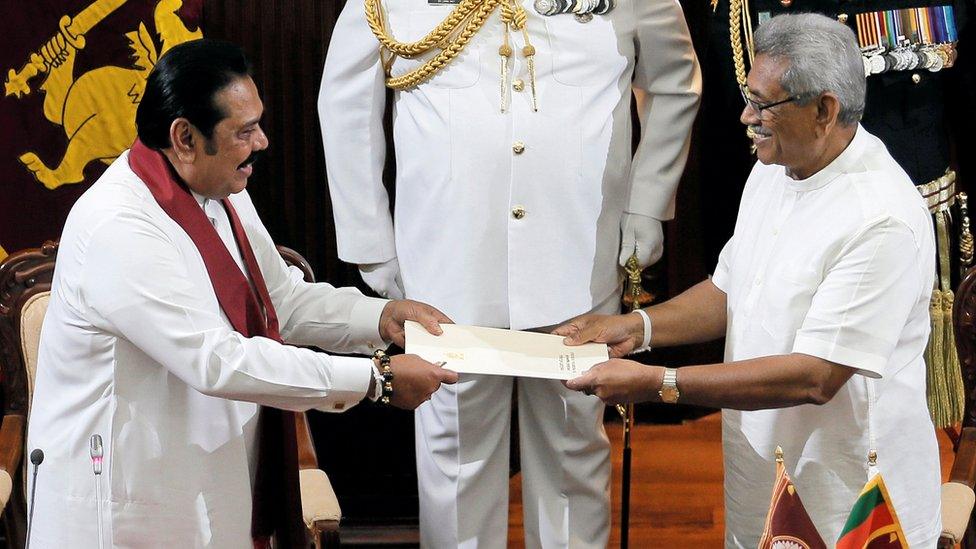 Sri Lanka"s President Gotabaya Rajapaksa hands over a document to his brother and former leader Mahinda Rajapaksa,