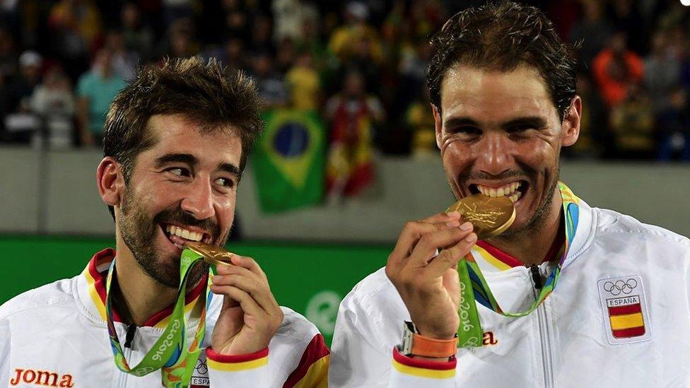 Gold medallists Spain's Rafael Nadal (R) and Spain's Marc Lopez bite their medal on the podium of the men's doubles final tennis match at the Rio 2016 Olympic Games