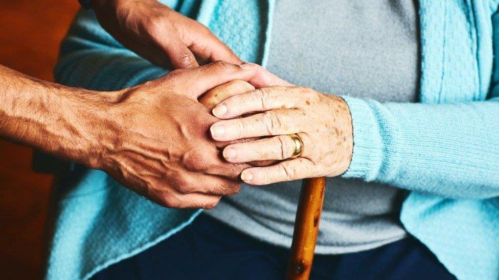 Close up hands, old person and carer