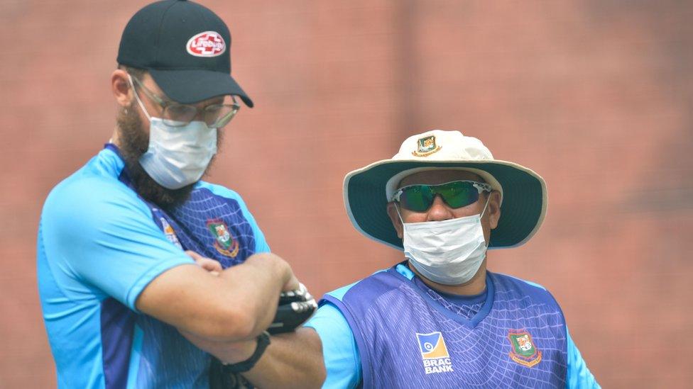 Bangladesh cricket team head coach Russell Domingo (R) and bowling coach Daniel Vettori wearing face masks watch the team during a practice session at Arun Jaitley Cricket Stadium in Delhi on November 1, 2019,