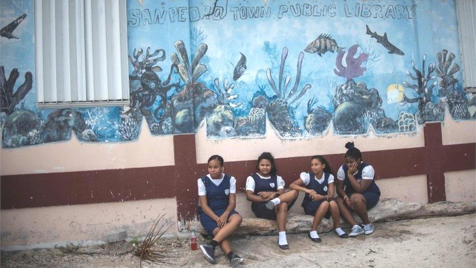 Students remain next to a mural of the Hol Chan Marine Reserve coral reef in the outskirts of San Pedro village, in Ambergris Cay, Belize, on June 7, 2018