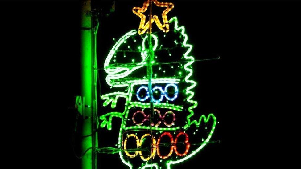 Photo of Christmas light in the shape of a big green dinosaur.