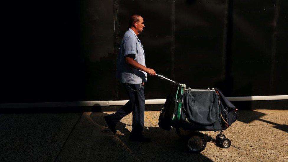 A US postal worker pushes a mail cart