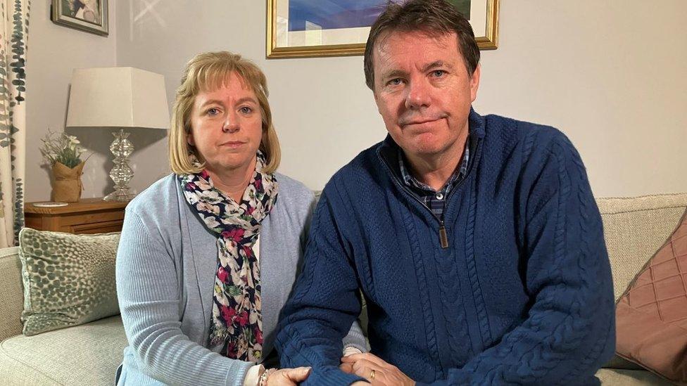 Alan and Catherine O'Sullivan sitting on the sofa and holding hands