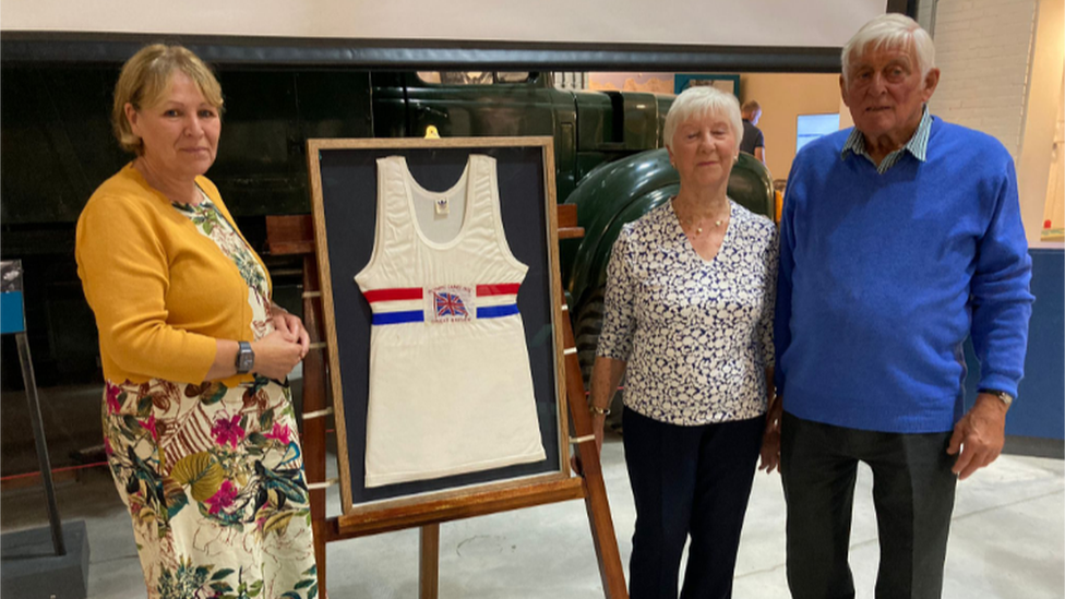 Three people standing around Jim Fox's vest