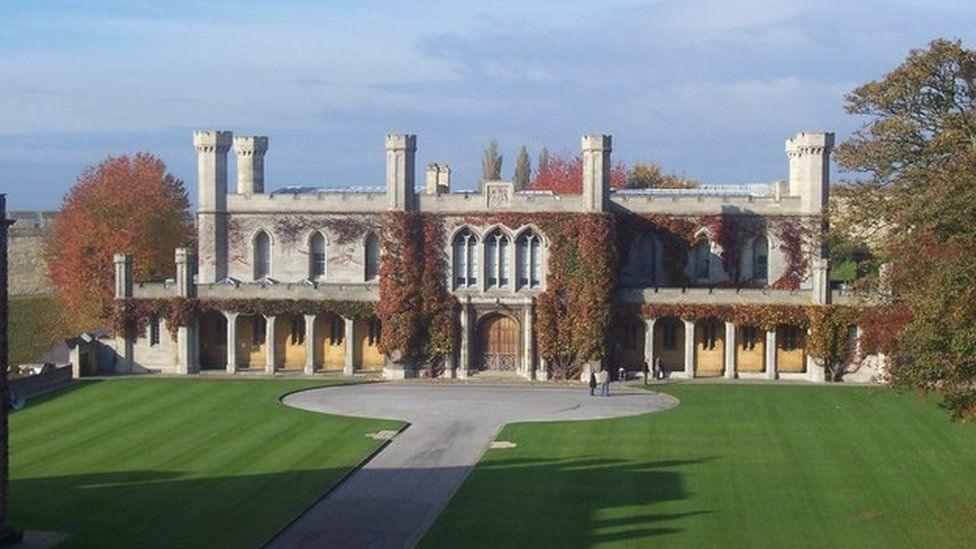 The exterior of Lincoln Crown Court a two-story Victorian Gothic building in light stone with crenellated turrets on the roof , columns on the ground floor and foliage growing around the doorway