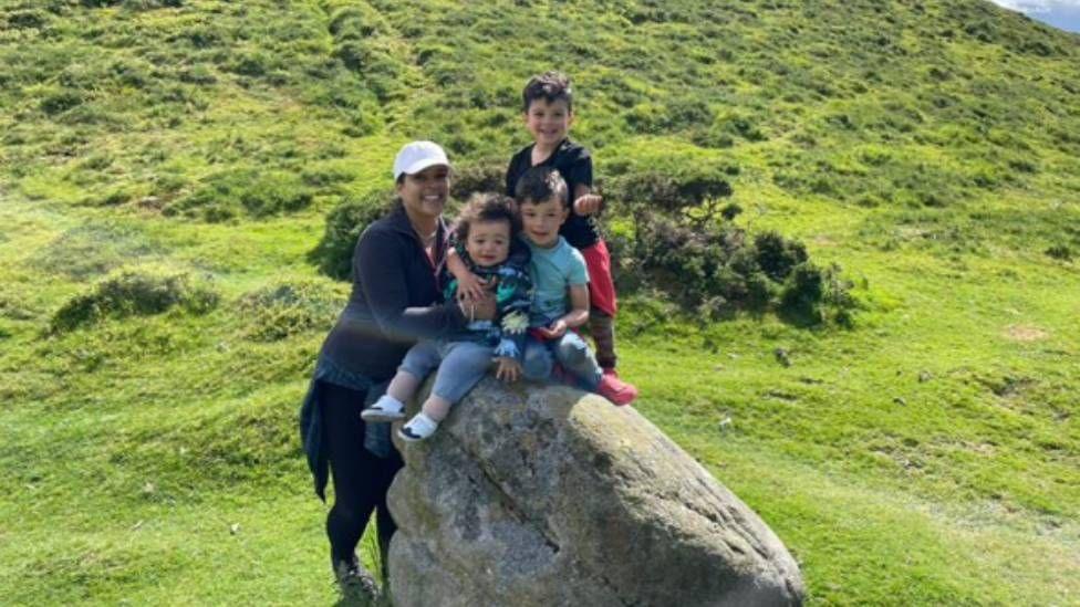 A pistillate   is seen lasting  successful  a tract  with 3  boys sat connected  a rock.