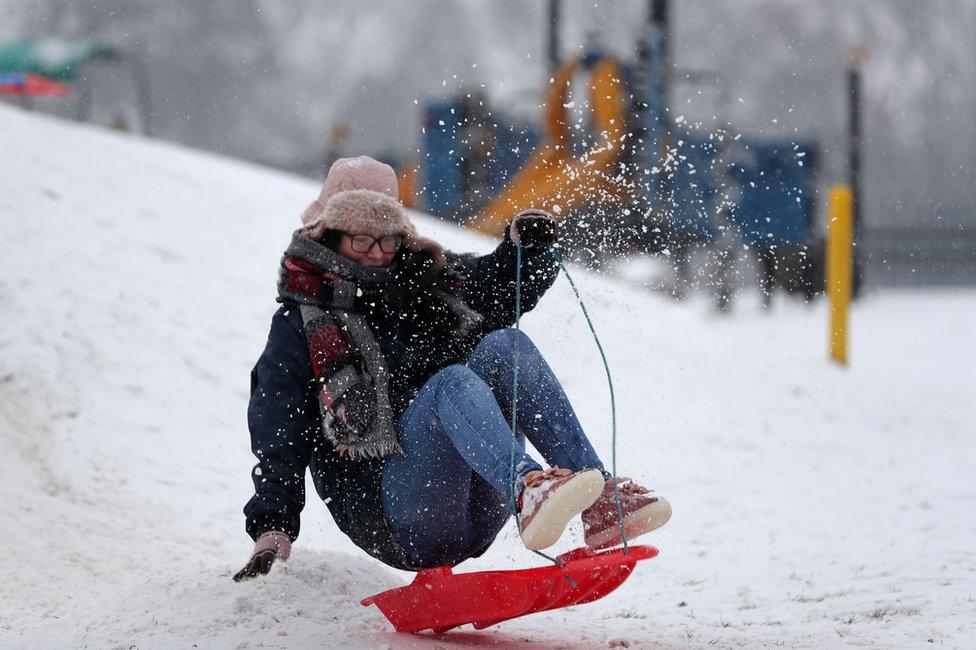 A woman travels on a sled down a slope at Farnborough in Hampshire