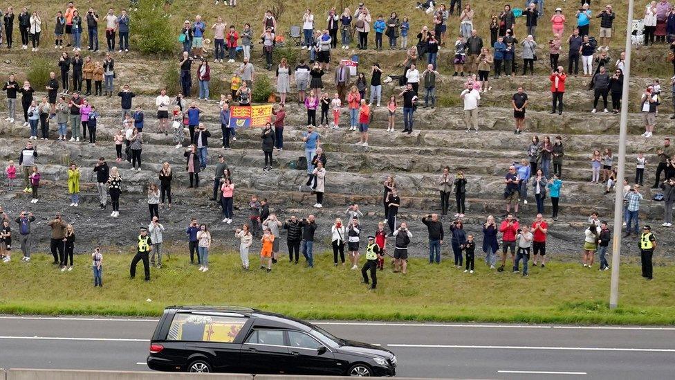 The hearse carrying the coffin of Queen Elizabeth II travels past crowds on its way into Edinburgh