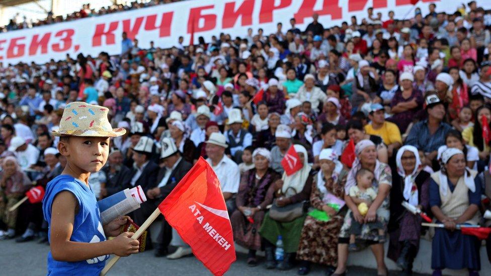 A Kyrgyz boy holds a party flag at a campaign event in a stadium in Belovodskoye