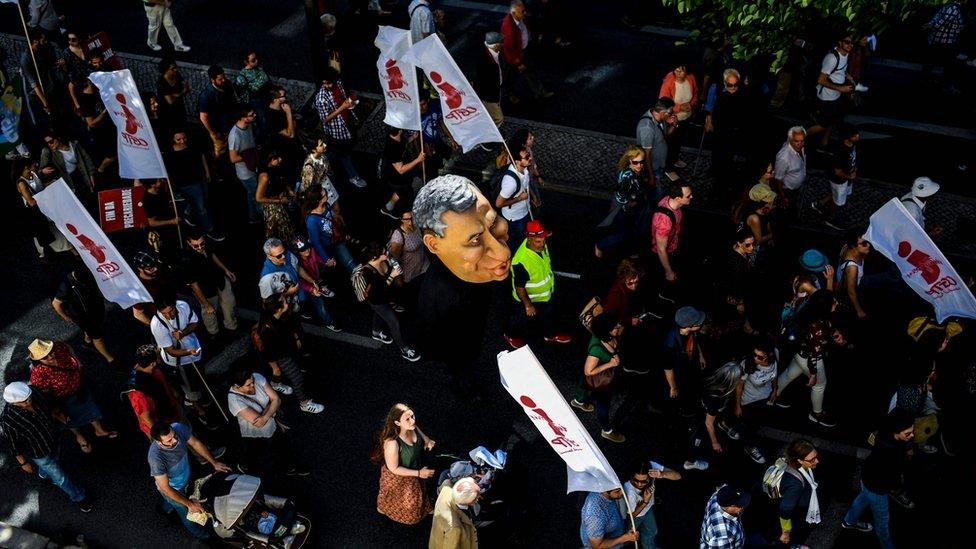 Protesters hold a puppet of Portuguese Prime Minister Antonio Costa during a rally in Lisbon