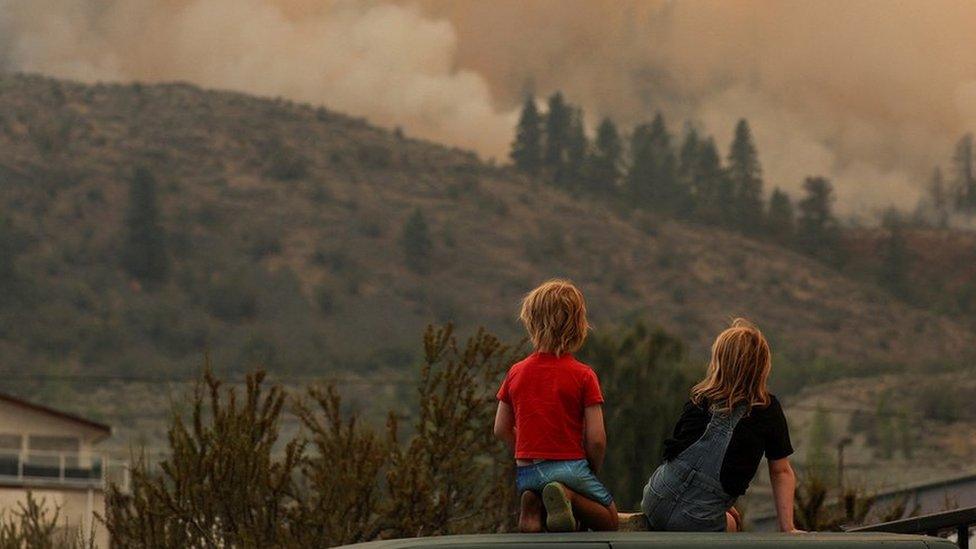 Local children watch firefighting efforts amid heavy smoke from the Eagle Bluff wildfire