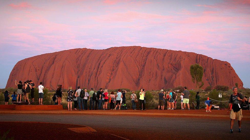 Visitors take photos at Uluru, one Australia's most popular tourist destinations.