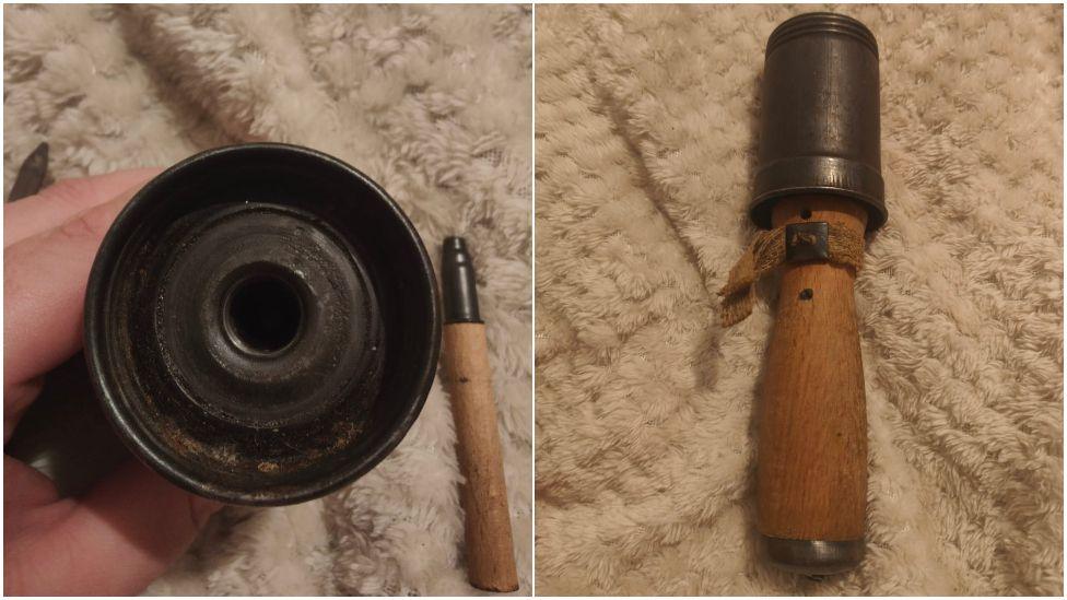 a hand holding stick grenade with  grey metal cylinder on top and a wooden handle of the bottom