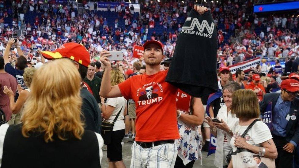 Trump fan holds up a CNN "fake news" shirt